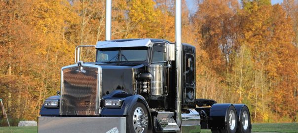 A photo of a black heavy truck in front of autumn foliage, for marketing the 2018 Wowtrucks calendar